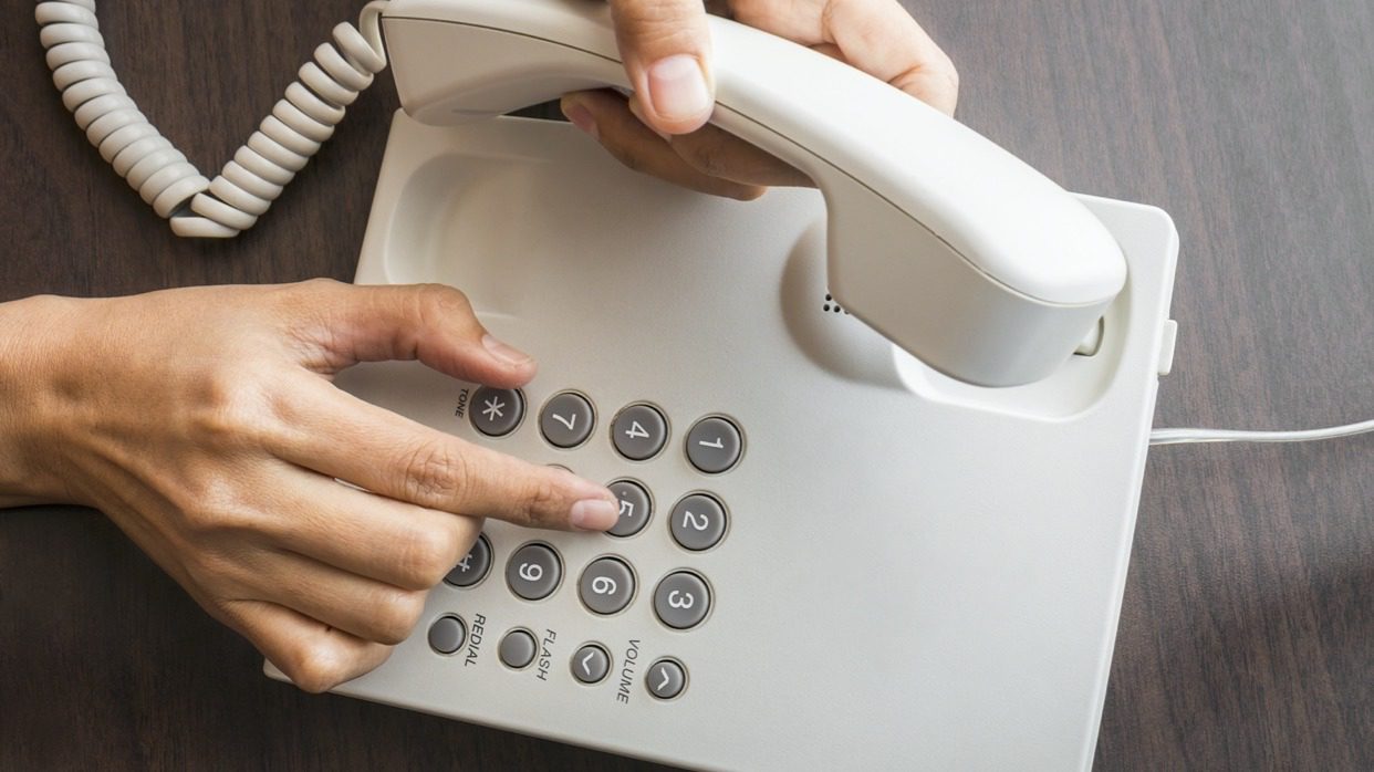 person pressing buttons on a PBX deskphone